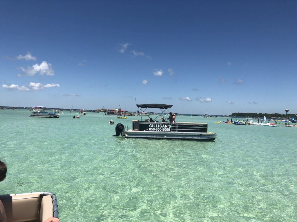 Gilligan’s pontoon boat anchored in the shallows at Crab Island in Destin, FL