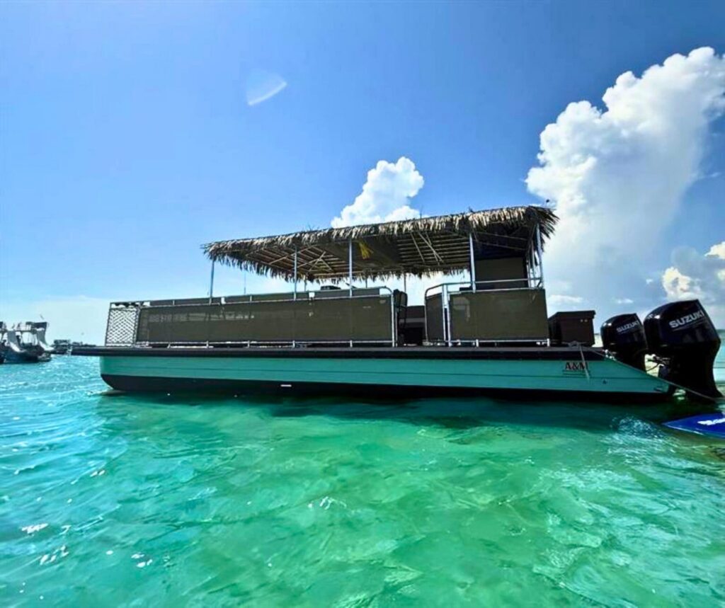 Gilligan’s tiki boat with its full thatched roof anchored at Crab Island in Destin, FL